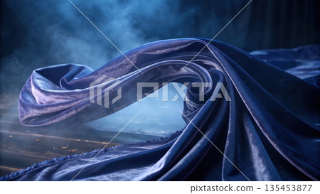Dramatic swirl of rich blue velvet fabric amidst ethereal blue mist Dramatic swirl of rich blue velvet fabric amidst ethereal blue mist 135453877