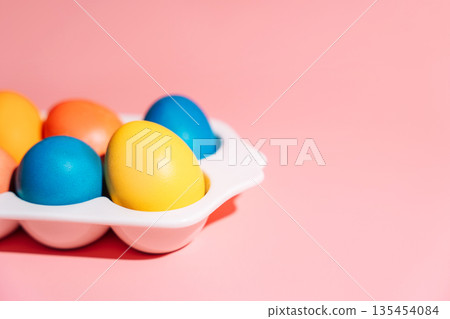 Easter eggs in carton on pink background with bright sunlight and shadows 135454084