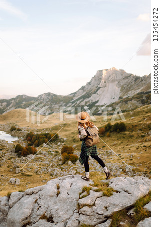 Happy woman stands on rocky terrain, gazing out at breathtaking landscape before her. Lifestyle. Happy woman stands on rocky terrain, gazing out at breathtaking landscape before her. Lifestyle. 135454272