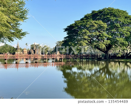 Wat Trapanggung in Sukhothai Historical Park and the red bridge reflected in the water 135454489