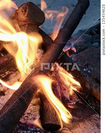 Atmospheric Outdoor Campfire with Bright Yellow Flames and Burning Logs 135454628