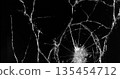 Front view photo of glass shattered by a bullet. Gunshot impact creates cracks, flying shards and dust isolated on black background. Perfect VFX overlay element or dramatic background. 135454712