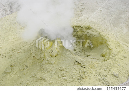 Fumarole fields on the slope of a volcano in the Kuril Islands, featuring surface openings emitting hot steam and yellow sulfur deposits. 135455677