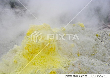 Geothermal fumarole field on a volcano slope in the Kuril Islands. Hot steam vents and bright yellow sulfur deposits. 135455739