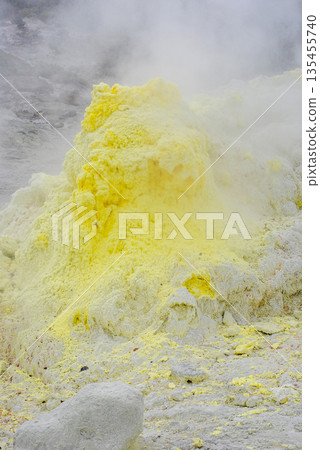 Geothermal fumarole field on a volcano slope in the Kuril Islands. Hot steam vents and bright yellow sulfur deposits. 135455740