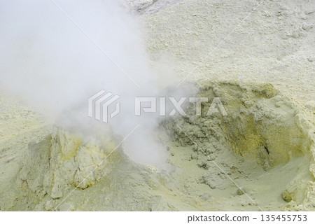 Geothermal fumarole field on a volcano slope in the Kuril Islands. Hot steam vents and bright yellow sulfur deposits. 135455753