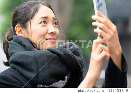 一位戴著圍巾的女士正在使用智慧型手機 一位戴著圍巾的女士正在使用智慧型手機 135455849