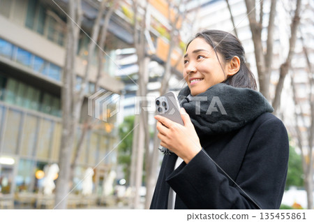 A woman wearing a scarf using a smartphone 135455861