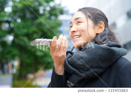 A woman wearing a scarf using a smartphone 135455863