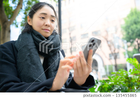 A woman wearing a scarf using a smartphone A woman wearing a scarf using a smartphone 135455865