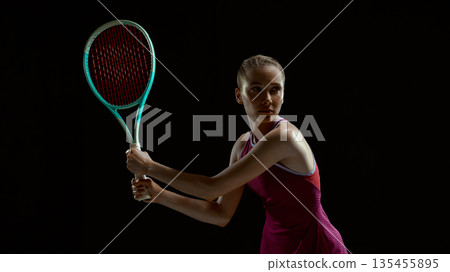 Female tennis athlete preparing for return shot on black background Female tennis athlete preparing for return shot on black background 135455895