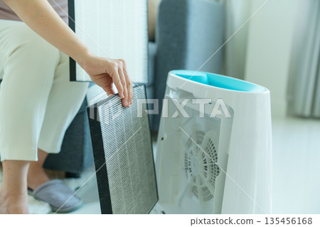 Woman changing filter of home air purifier. Woman changing filter of home air purifier. 135456168