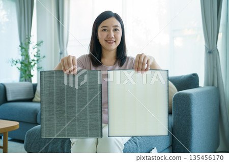 Asian woman showing dirty and clean air purifier filters for comparison. Asian woman showing dirty and clean air purifier filters for comparison. 135456170