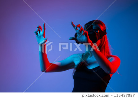 Woman Interacting With Virtual Reality Interface Using Both Hands, Advanced VR Technology, Gaming and Metaverse Experience Woman Interacting With Virtual Reality Interface Using Both Hands, Advanced VR Technology, Gaming and Metaverse Experience 135457087
