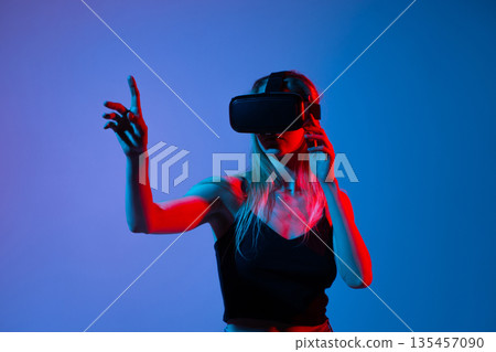 Side view of woman using VR headset and gesturing with finger, immersive virtual experience and future technology Side view of woman using VR headset and gesturing with finger, immersive virtual experience and future technology 135457090