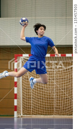 一名來自手球俱樂部的女高中生在空中扭動身體，射門得分。 135457503