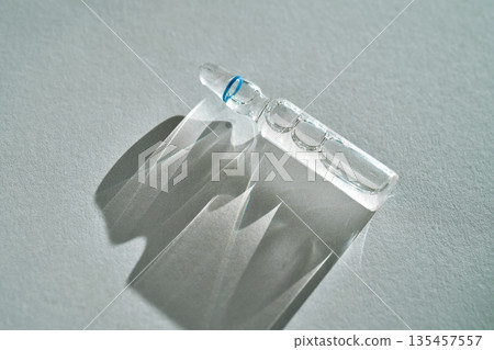 Ampoule casting clear shadow on gray background Ampoule casting clear shadow on gray background 135457557