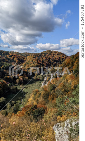 Early autumn colors begin to appear in a mountain valley with green hills, forested slopes, limestone cliffs, and scattered cottages. Early autumn colors begin to appear in a mountain valley with green hills, forested slopes, limestone cliffs, and scattered cottages. 135457593