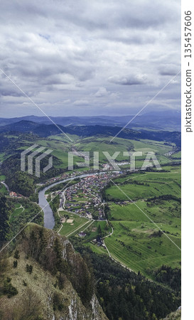 Scenic aerial view of mountain valley with winding river, green forests and small villages. Beautiful natural landscape, perfect travel background and environment concept. 135457606