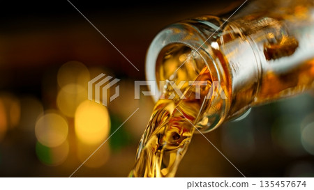 Pouring Whiskey from Bottle . Stream of Golden Liquid Flows on a Pub Pouring Whiskey from Bottle . Stream of Golden Liquid Flows on a Pub 135457674