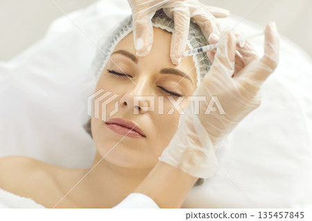 Cosmetologist makes rejuvenating anti wrinkle injections on face of beautiful woman. 135457845