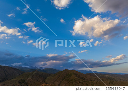 Serene mountain landscape under clear blue sky with clouds 135458047