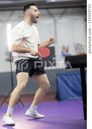 Excited man playing table tennis celebrating victory 135458723