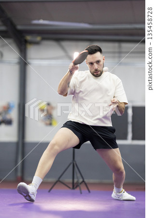 Determined man playing table tennis hitting ball Determined man playing table tennis hitting ball 135458728