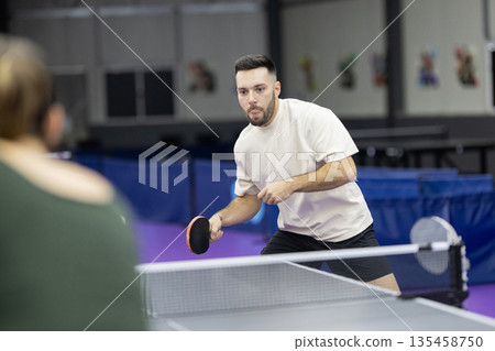 Concentrated athlete playing competitive table tennis game 135458750
