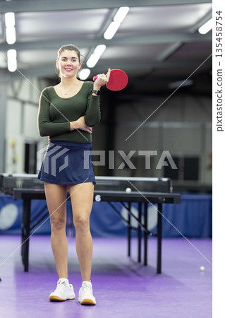 Young woman smiling holding table tennis paddle indoors 135458754