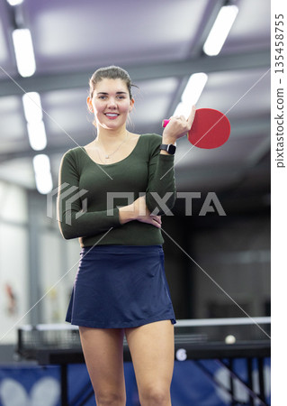 Young woman smiling while holding table tennis paddle Young woman smiling while holding table tennis paddle 135458755