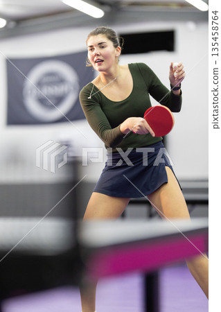 Young woman playing table tennis preparing for serve Young woman playing table tennis preparing for serve 135458764