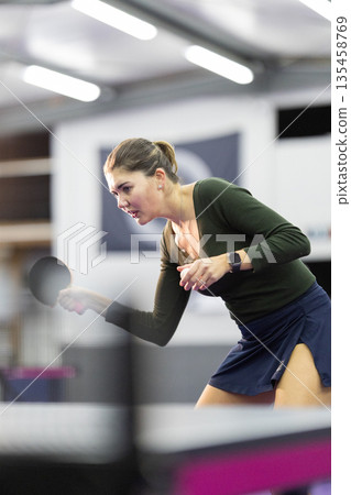 Young woman playing table tennis game indoors Young woman playing table tennis game indoors 135458769