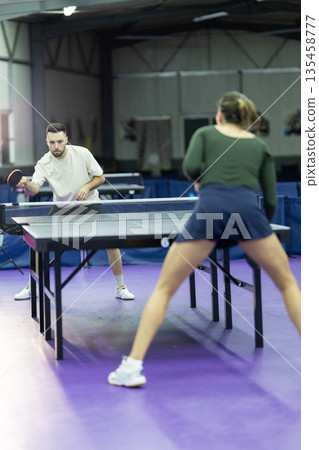 Athletes playing table tennis in an indoor training facility Athletes playing table tennis in an indoor training facility 135458777