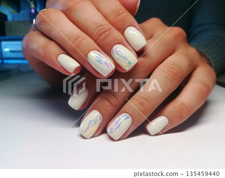 White Holographic Manicure Iridescent Nails. Elegant white gel manicure with holographic iridescent foil accents on almond nails. Trendy nail art for beauty, fashion, cosmetics concepts White Holographic Manicure Iridescent Nails. Elegant white gel manicure with holographic iridescent foil accents on almond nails. Trendy nail art for beauty, fashion, cosmetics concepts 135459440