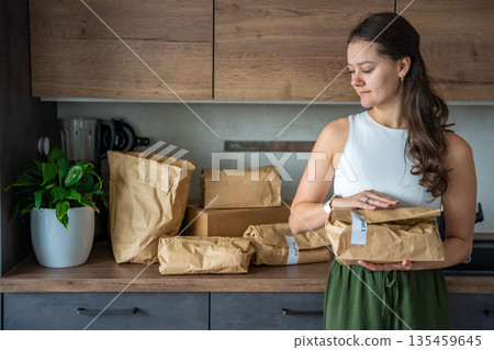 Woman holding a labeled grocery bag with the word Recept, meaning recipe in another language. Concept of convenient meal kit delivery with pre-portioned, ready-to-cook ingredients. 135459645