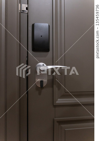 Hotel room door with electronic key card lock and metal handle, modern security access system and minimalist interior design Hotel room door with electronic key card lock and metal handle, modern security access system and minimalist interior design 135459736