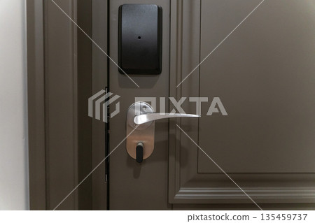 Hotel room door with electronic key card lock and metal handle, modern security access system and minimalist interior design Hotel room door with electronic key card lock and metal handle, modern security access system and minimalist interior design 135459737