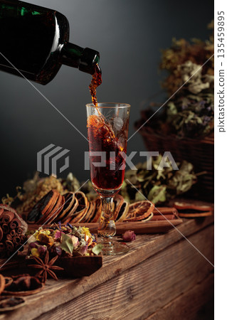 Herbal balm or tincture is poured from a vintage bottle into a glass. Herbal balm or tincture is poured from a vintage bottle into a glass. 135459895