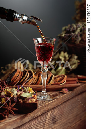 Herbal balm or tincture is poured from a vintage bottle into a glass. 135459897