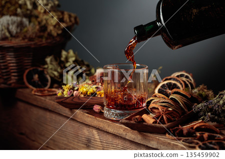 Herbal balm or tincture is poured from a vintage bottle into a glass. Herbal balm or tincture is poured from a vintage bottle into a glass. 135459902
