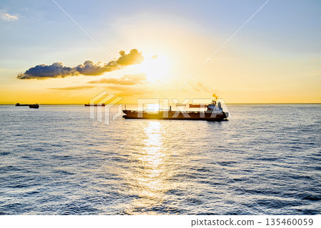 Cargo ships sailing at sunset, towards the port of Barcelona Cargo ships sailing at sunset, towards the port of Barcelona 135460059