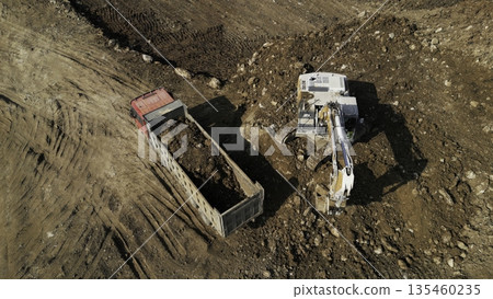Excavator loading dump truck with soil on construction site. Clip 135460235
