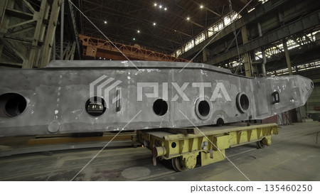 Heavy metal ship component moving on wheeled platform in factory. Stock clip 135460250