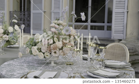 Elegant wedding table setting with flower centerpiece in front of villa. Action Elegant wedding table setting with flower centerpiece in front of villa. Action 135460275