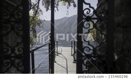 Admiring the Beautiful Lake View from the Garden Gate, Surrounded by Scenic Mountains. Action 135460296