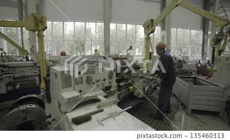 Factory worker operating lathe machine in manufacturing plant. Stock clip Factory worker operating lathe machine in manufacturing plant. Stock clip 135460313