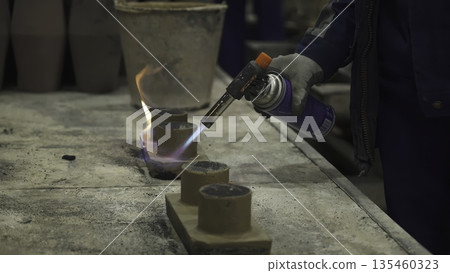 Foundry worker using blowtorch on small clay cylinders. Stock clip 135460323