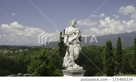 White statue overlooking green valley under blue sky. Action White statue overlooking green valley under blue sky. Action 135460334
