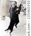 A vintage portrait of an aunt and nephew in snowy weather. The young woman holds the baby, who is frightened by a dog. Retro photo from 1969. 135460350
